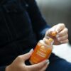 Close-up of a person holding turmeric and ginger gummies in a bottle with natural lighting.