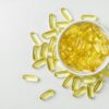 High-angle shot of omega-3 fish oil capsules in a ceramic bowl on a white background.