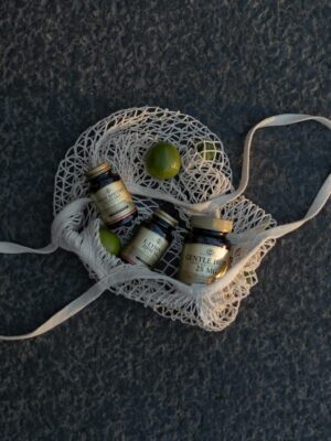 Photo by Алеся Горбунова Top view of mineral supplement bottles in a mesh bag with limes on textured surface.